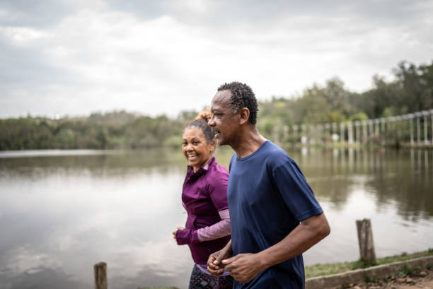 coppia anziana che fa jogging in un parco - senior adult senior couple exercising african ethnicity foto e immagini stock