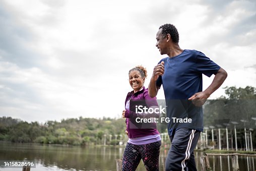 istock Senior couple jogging in a park 1415828696
