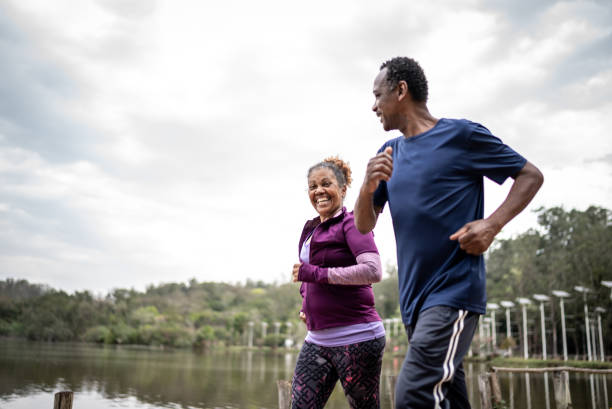 Senior couple jogging in a park Senior couple jogging in a park exercise routine stock pictures, royalty-free photos & images