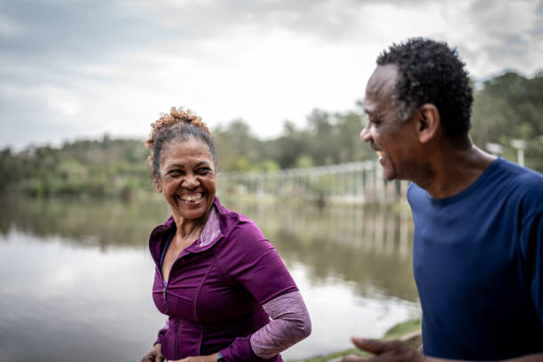 coppia anziana che fa jogging in un parco - senior adult senior couple exercising african ethnicity foto e immagini stock