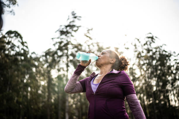 istock Senior woman drinking water in a park 1415829609