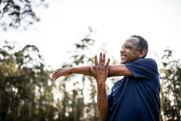 hombre mayor estirándose en un parque - senior adult relaxation exercise healthy lifestyle exercising fotografías e imágenes de stock