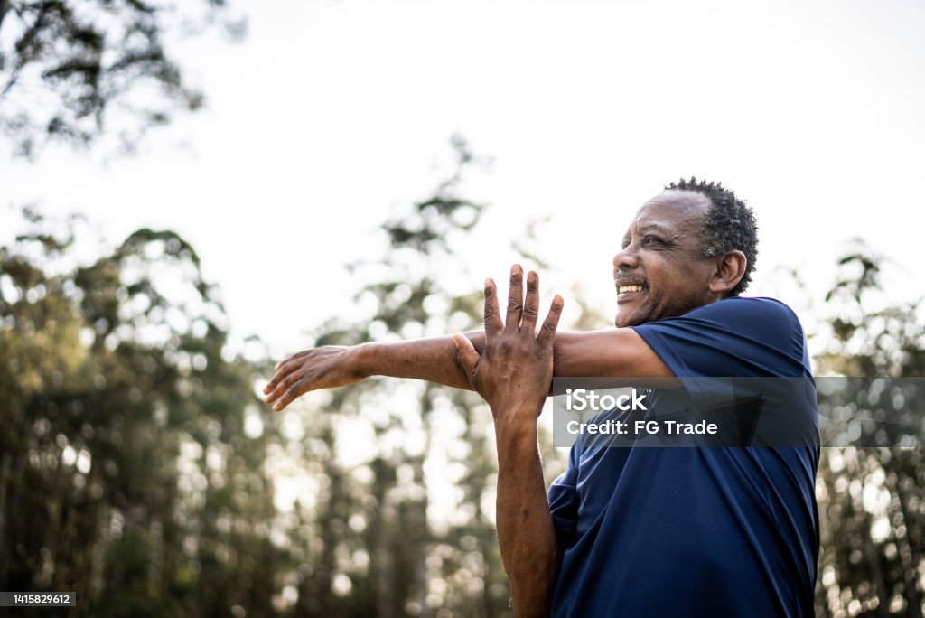 Senior man stretching in a park Exercising Stock Photo