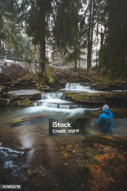 Clear Water Photographed With Long Exposure Time Through Flowing Rocks Covered With Moss With Autumn Colours Of Leaves And Tourist Sits Next To Waterfall Krasna Beskydy Mountains Czech Republic Stock Photo - Download Image Now