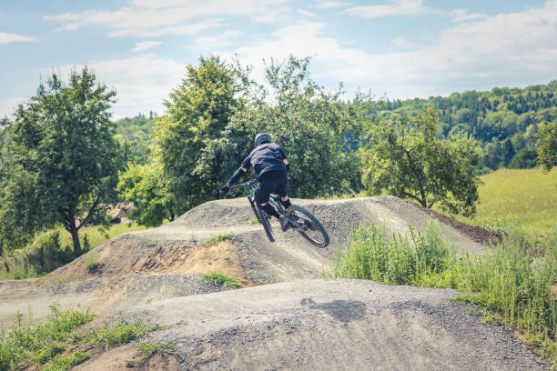 A male motocross rider heads pops a wheelie while riding up a trail in British Columbia, Canada.