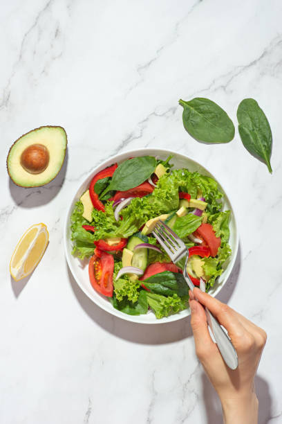 istock Vegetable salad with avocado in a white plate on a gray background 1415836746