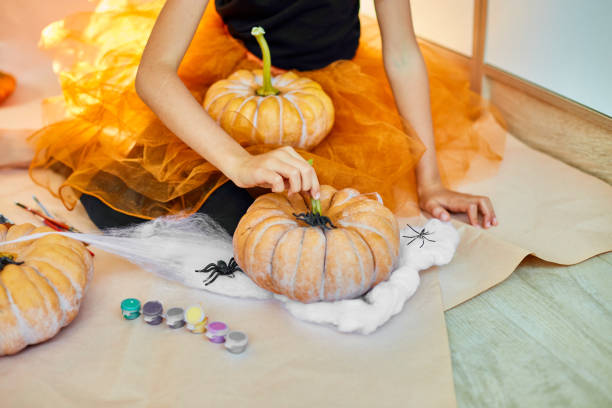 istock Child play with spider, decorating a pumpkin at home 1415837329