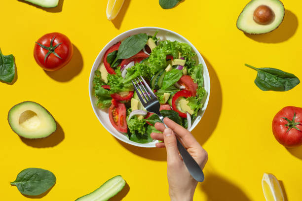 istock Vegetable salad with avocado in a white plate on a yellow background. Cooking. Diet. 1415837669