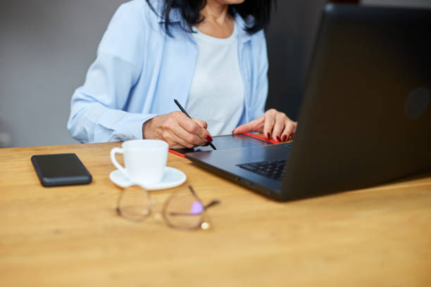 istock Senior woman designer using graphics tablet and stylus, working at laptop 1415838109