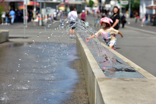 A girl cools off at a water feature in Vienna (Favoriten district)