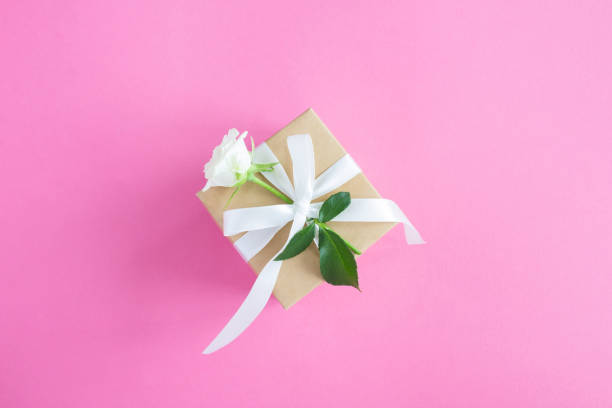 istock Gift box and with white rose on the pink background. Top view. Copy space. 1415841633