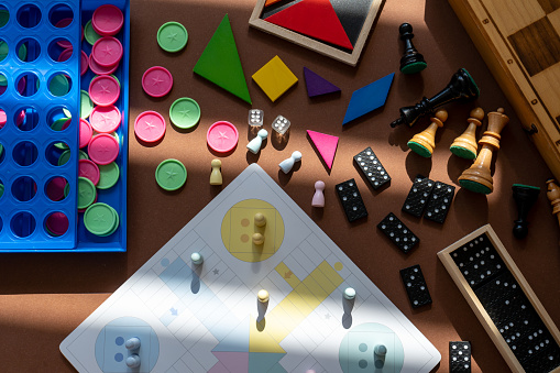 Different desktop games, figures, dices, parts on the brown table. Home entertaiment, indoor games