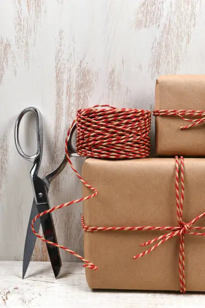 Closeup of plain brown paper wrapped Christmas presents with scissors and twine.