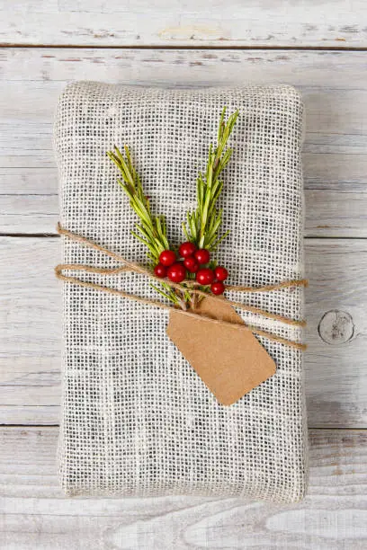 Fabric wrapped Christmas present on a rustic wood table.