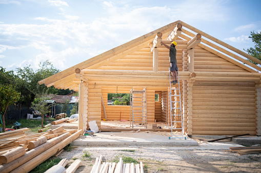 Dedicated builder working on log cabin construction site.