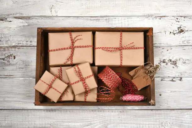 Wood box on filled with plain brown paper wrapped Christmas presents with twine and tags.
