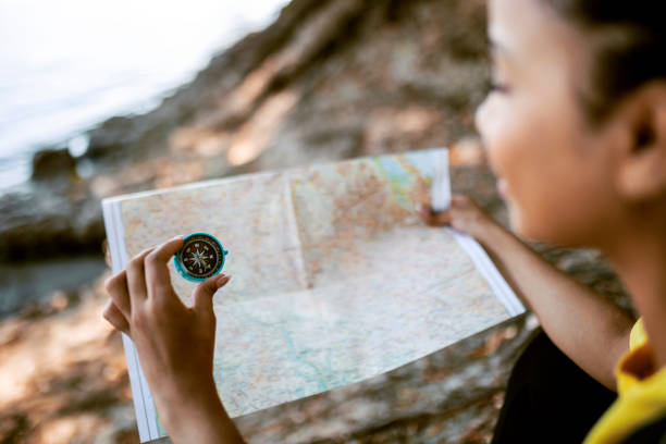 istock Young woman hiking in nature exploring a map with compass 1415846693