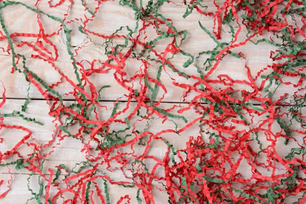 Strands of shredded crepe paper on a rustic white wood background.  A colorful Christmas background image.