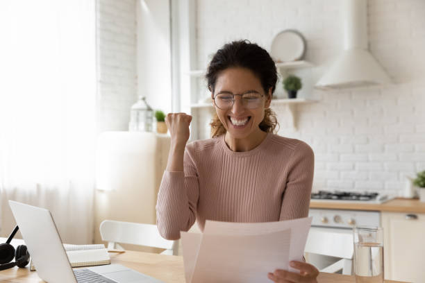 Woman sit in kitchen read paper from bank feels excited stock photo