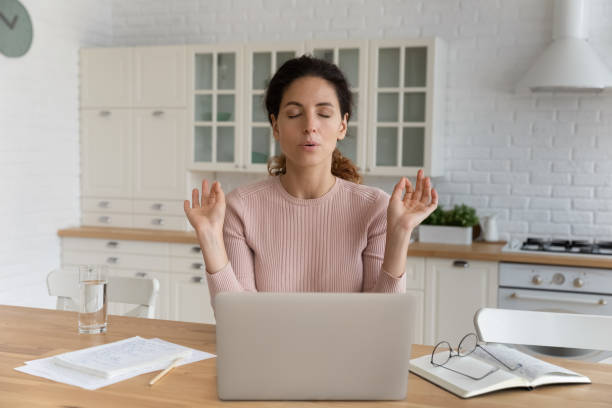 Woman sit near laptop makes calming exercises to reduce stress Young Hispanic businesswoman sit at table in kitchen near computer closed eyes makes breathing technique calming exercises. Stress management, anxiety relief due business problem. Self-control concept copek stock pictures, royalty-free photos & images