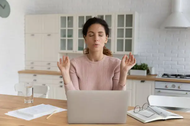 Photo of Woman sit near laptop makes calming exercises to reduce stress