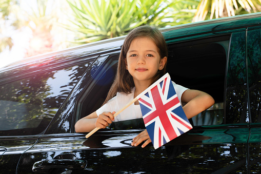 Girl holding British flag in the car.