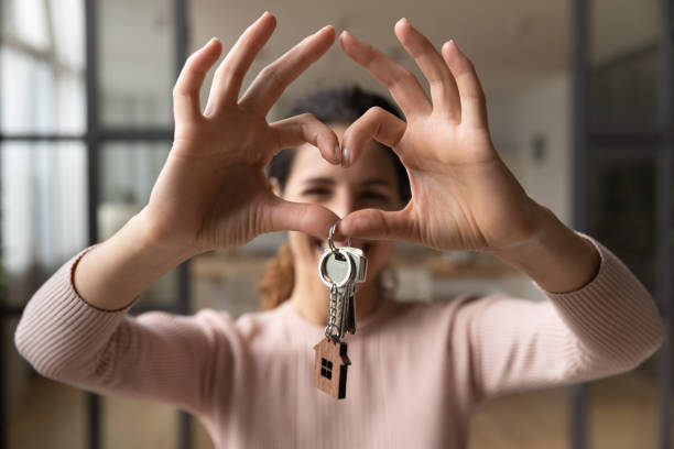 mujer feliz sostiene las teclas hace símbolo del corazón con los dedos unidos - real estate agent fotografías e imágenes de stock