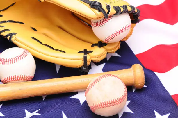 Baseballs glove and bat on American Flag in horizontal format.