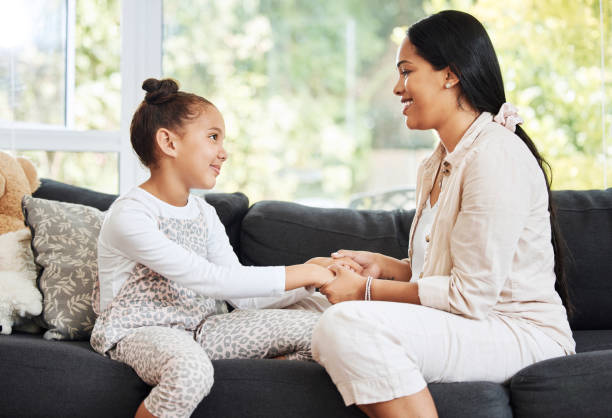 istock Happy, smiling and talking mother and daughter bonding, holding hands and showing affection while relaxing on the couch together at home. Parent giving advice, support and care to a little girl 1415853883