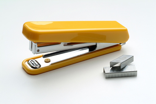 Yellow stapler, and staples on white background.