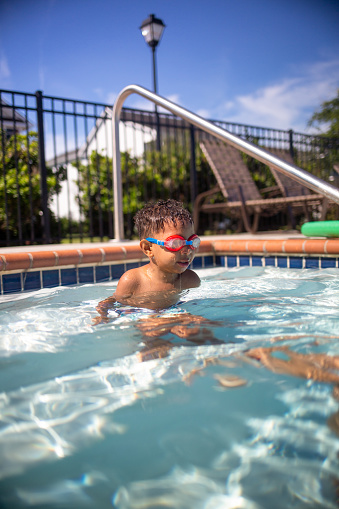 Multi race Boy learning to swim. \nSupervised by Mom. \n\nShallow DOF