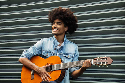 African american man with african hairstyle playing guitar