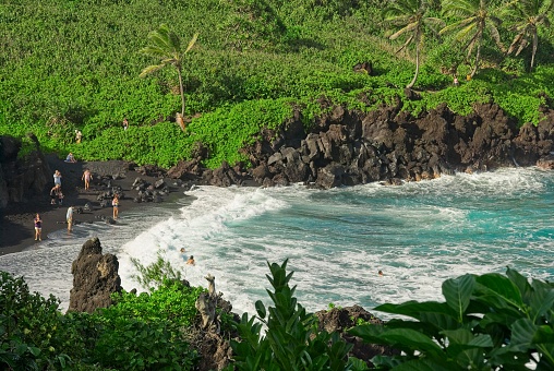 Black sand beach at Waianapanapa  state park along Hana highway, Maui Hawaii. Beach goers flock to the turquoise waters at this popular park.