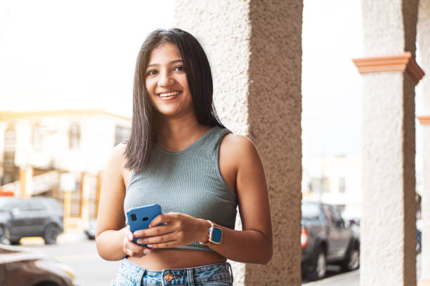 istock Young latin american young woman using a mobile looking away. 1415862934