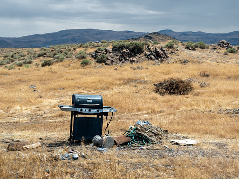 Trash including an abandoned BBQ, wire, cans and bottles litter the Nevada desert in the mountains above Reno.