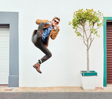 Portrait of excited handsome young man jump kicking outdoors