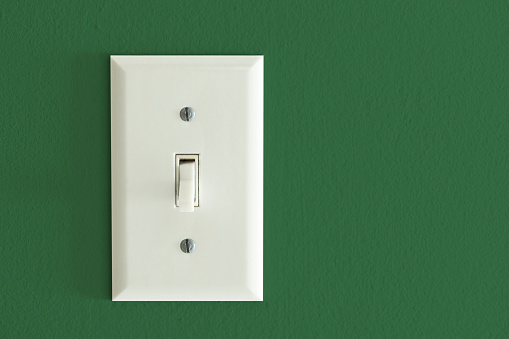 Light switch on a green wall.