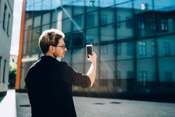 istock Young man taking picture of modern building 1415869085