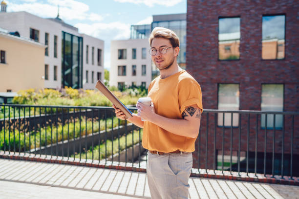 istock Student with notepad and takeaway drink on street 1415869135
