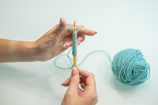 Woman is sitting on the sofa with a cup of tea, a slice of homemade cake and knitting