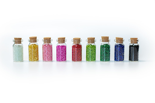 small transparent bottles with colorful beads on a white background.
