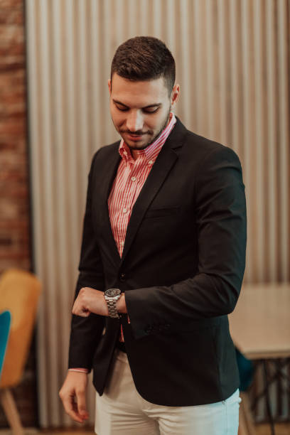 istock Portrait of a young modern manager looking at the clock while posing in a modern office. Selective focus 1415874736