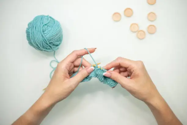 Photo of Women's hands knit on a white background. Knitting on knitting needles from wool and cotton. handmade