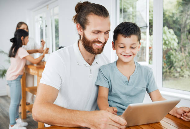 istock Learning with tablet, watching educational videos and searching the internet with father and son relaxing together at home. Smiling, curious and happy boy browsing the web and having fun with parent 1415877694