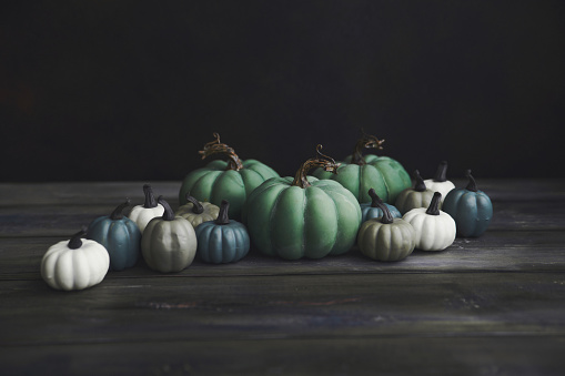 Fall Thanksgiving background with a collection of green toned pumpkins on wood. Space for copy