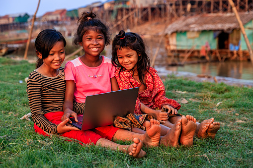 Happy Cambodian girls using laptop in village near Tonle Sap, Cambodia