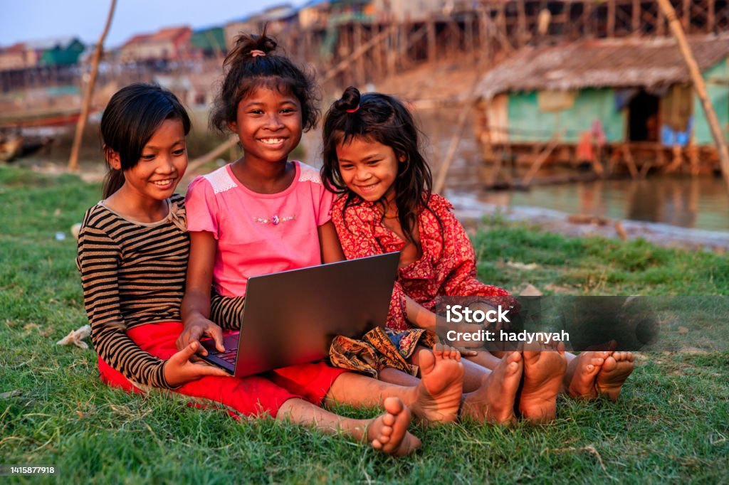 Happy Cambodian girls using laptop in village, Cambodia Happy Cambodian girls using laptop in village near Tonle Sap, Cambodia Village Stock Photo