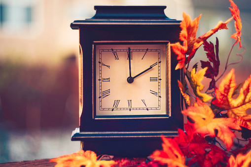 Retro clock with fall leaves. Daylight savings time