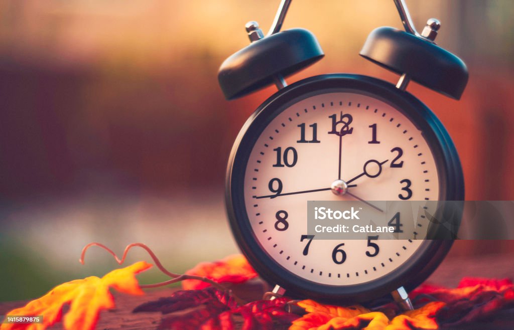 Alarm clock with fall leaves. Daylight savings time Daylight Saving Time Stock Photo