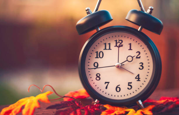 alarm clock with fall leaves. daylight savings time - 時區 個照片及圖片檔